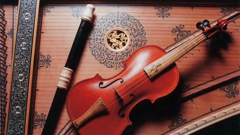 Image of baroque flute and baroque violin lying on the soundboard of a harpsichord